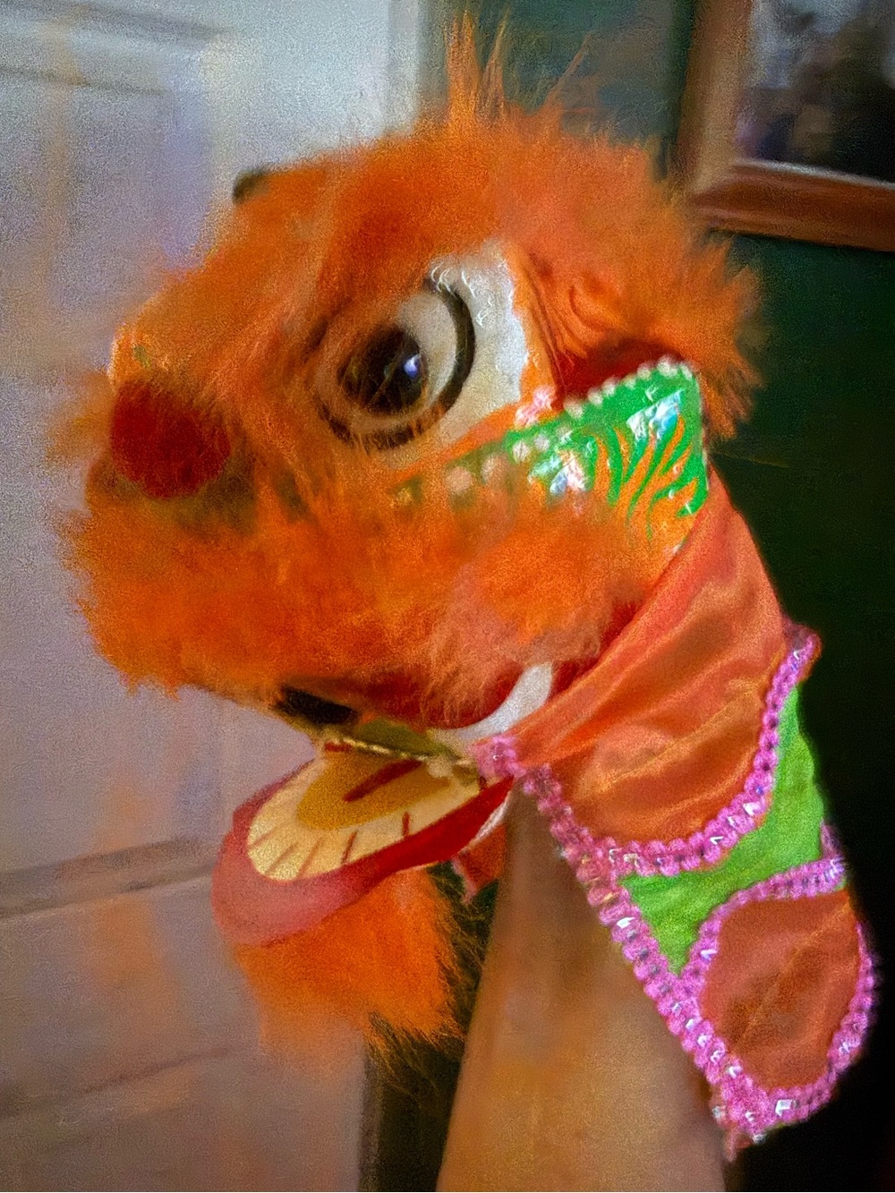 A traditional orange Chinese Lion Dance Puppet, which is a handmade folk art toy